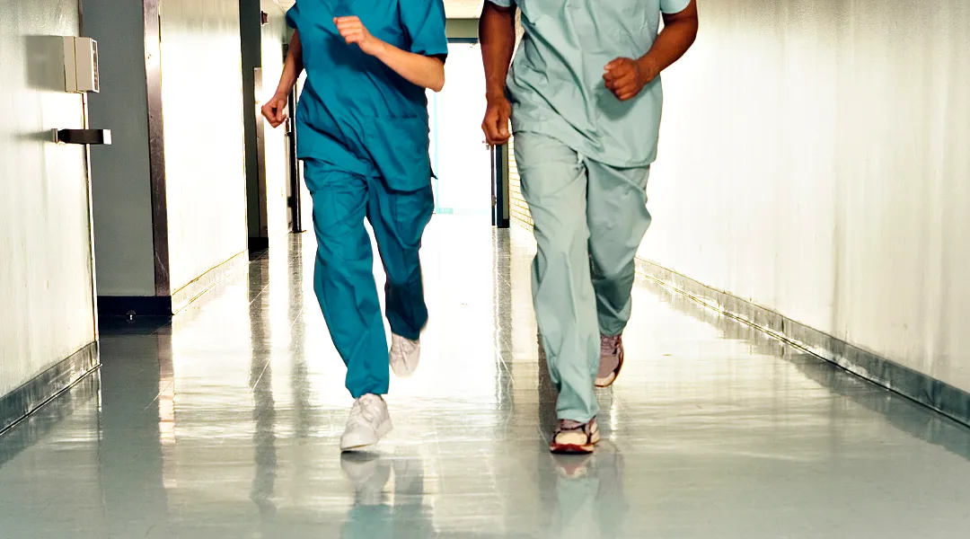 Kaksi hoitajaa juoksee sairaalan käytävällä.