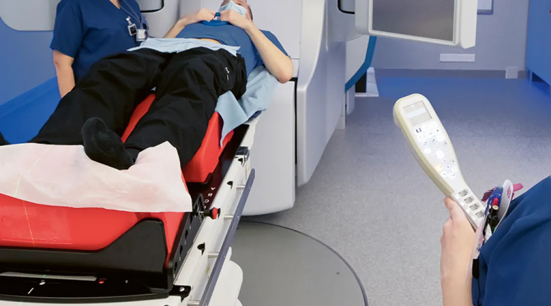 Kaksi röntgenhoitajaa laittaa potilasta röntgenlaitteeseen