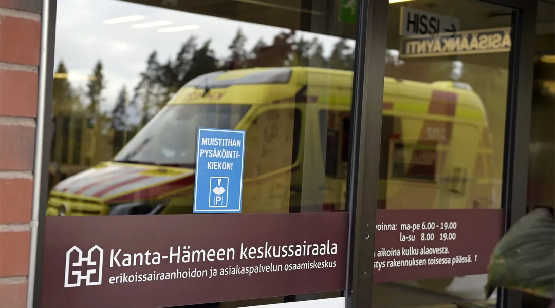 Ambulanssin kuva heijastuu Kanta-Hämeen keskussairaalan lasiovista.