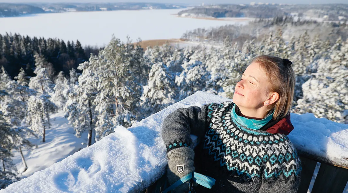 Vivi Aaltonen nautiskelee lumisessa maisemassa näköalapaikalla.