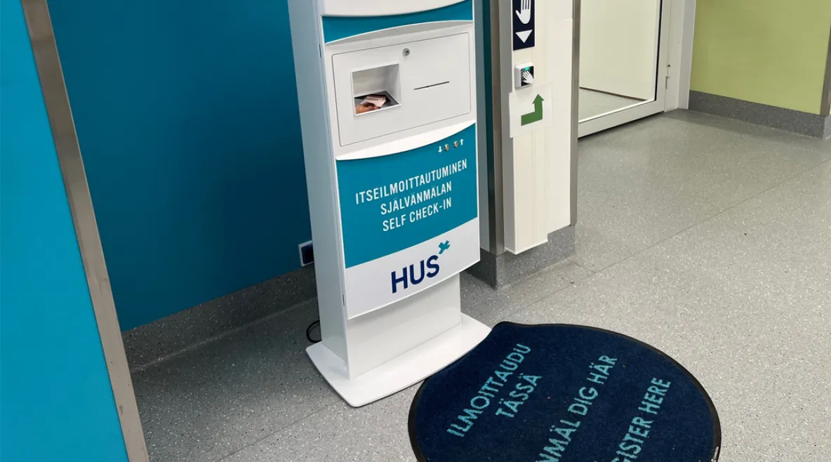 Husin ilmoittautumisautomaatti käytävällä.