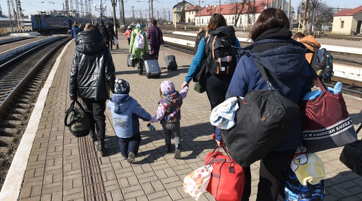 Ukrainalaisia pakolaisia rautatieasemalla raiteiden vieressä tavaroineen.