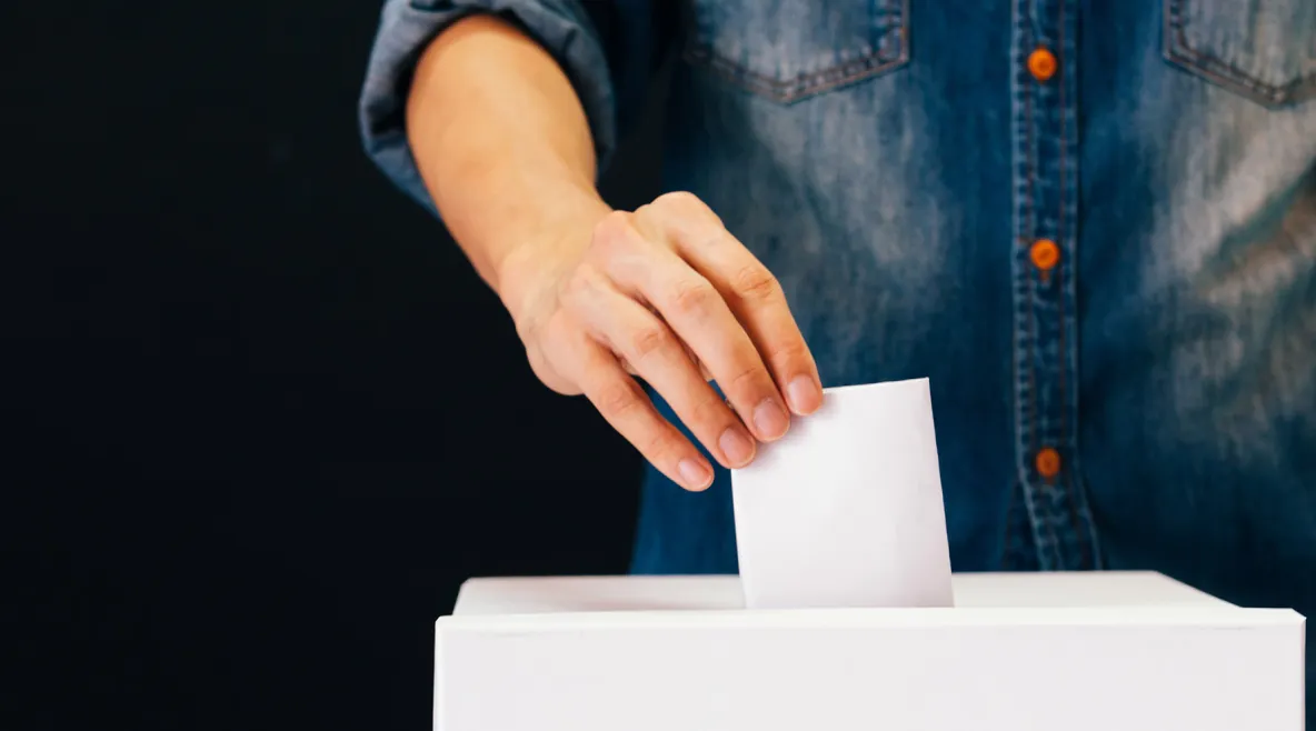 Ihminen sujauttaa äänestyslipuketta laatikkoon