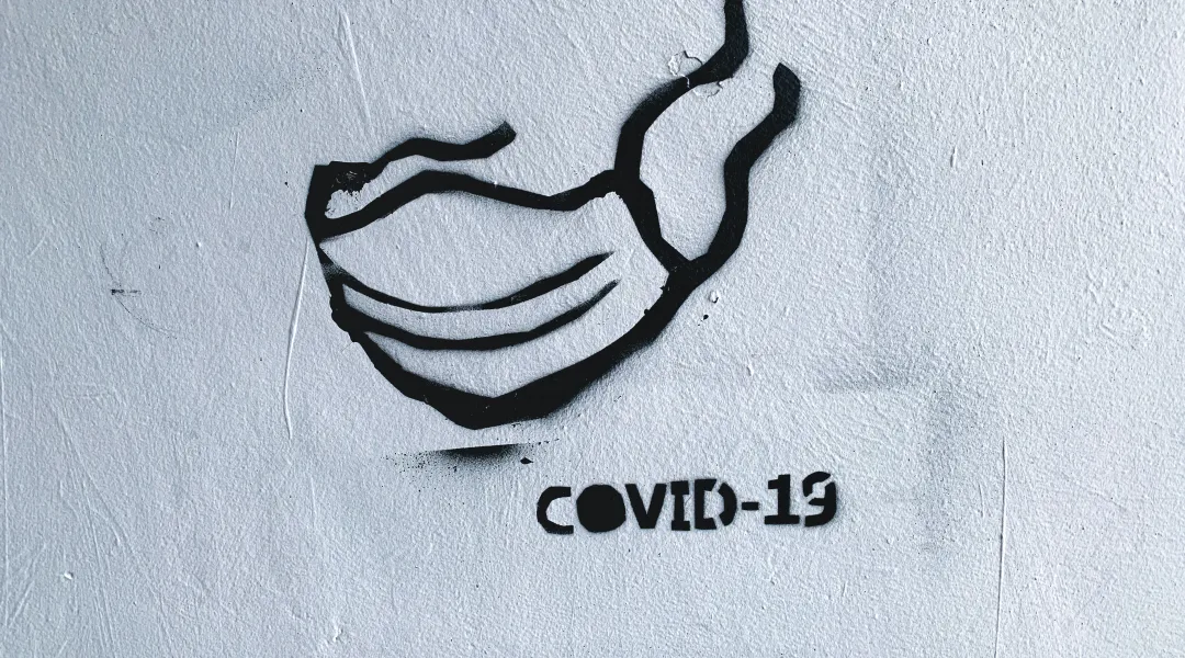 Graffiti, jossa maski ja teksti Covid-19.