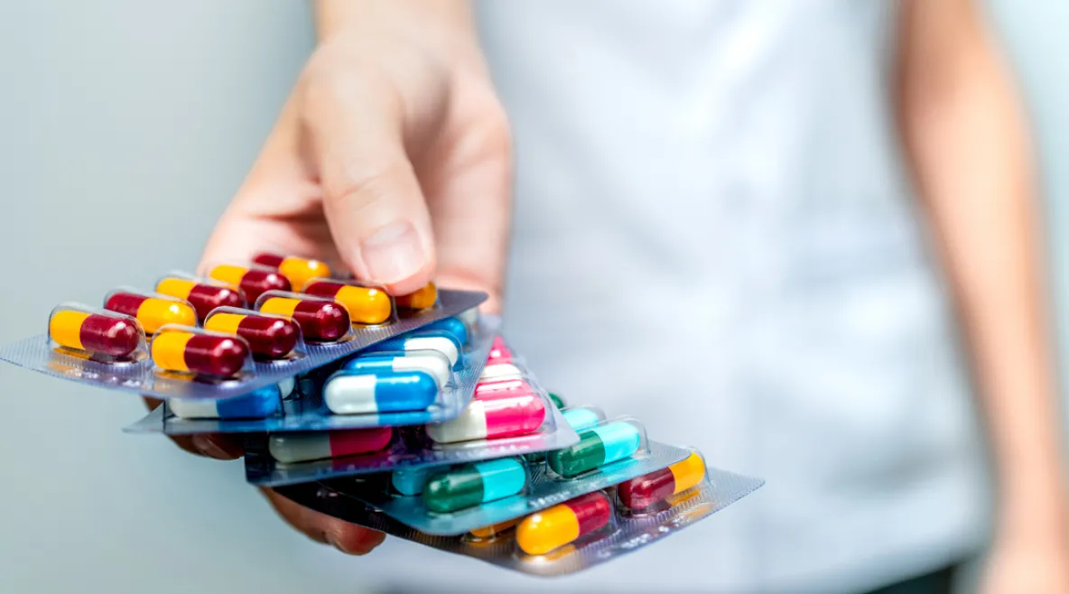 Apteekkihenkilökunta tai lääkäri pitelee kädessään antibioottikapselipillereitä ja antaa potilaalle tai lääkkeille