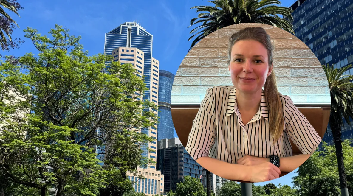 Tutkimuskoordinaattori Jenna Vartiainen. Taustalla Australian maisemaa ja korkeita kerrostalorakennuksia puiden katveessa.
