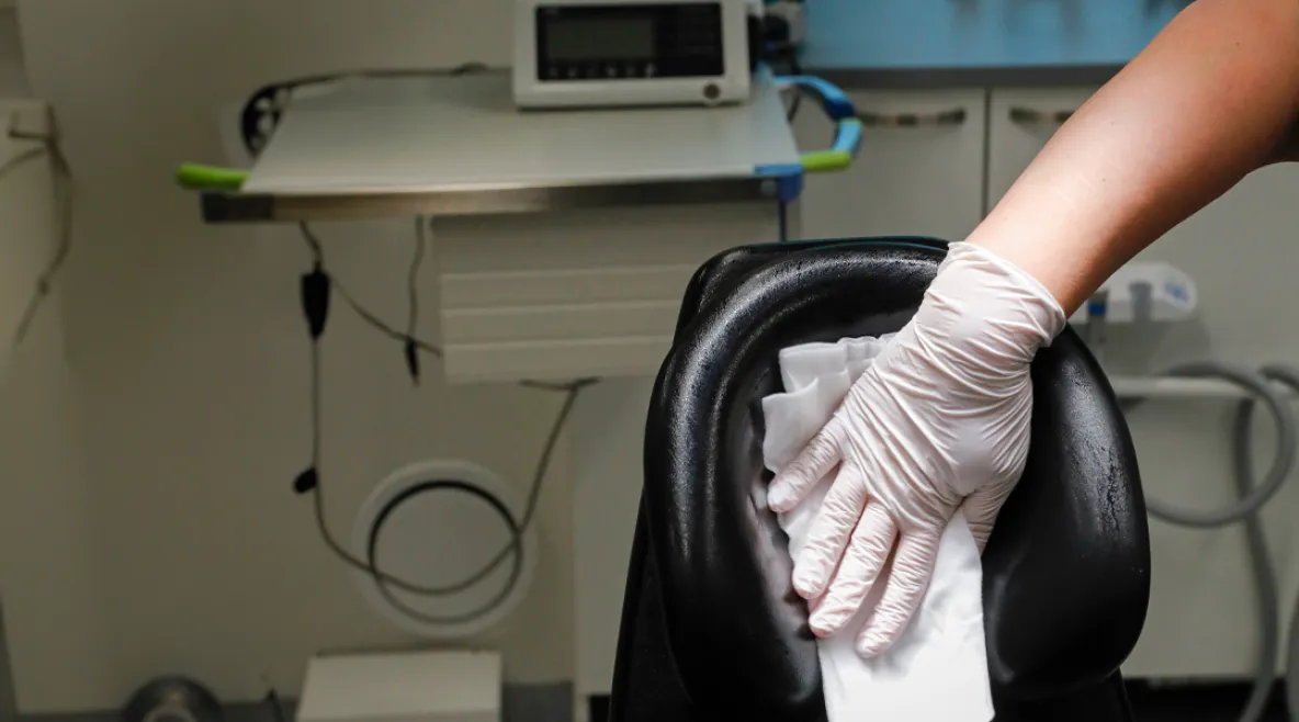 Suuhygienisti puhdistamassa puhdistusliinalla hammashoitotuolia.