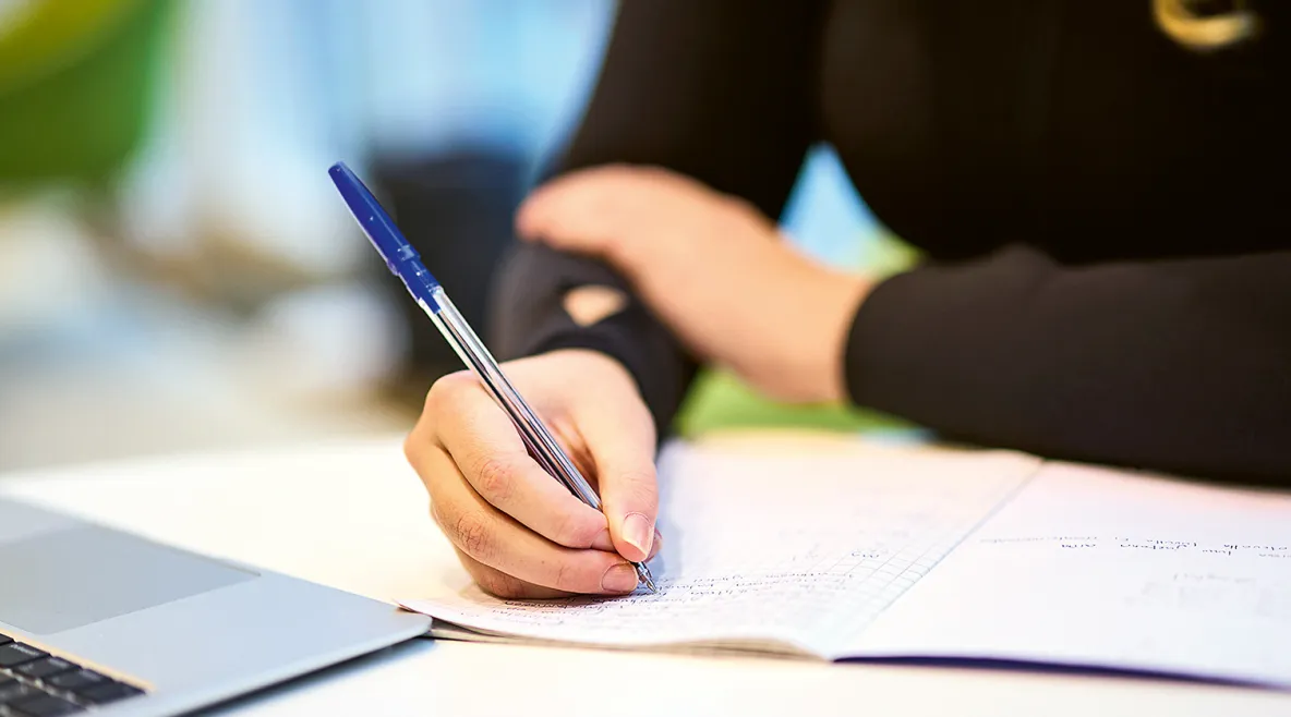 Cecilia Suomi laskemassa lääkelaskuja. Lähikuva käsistä ja laskuvihkosta.