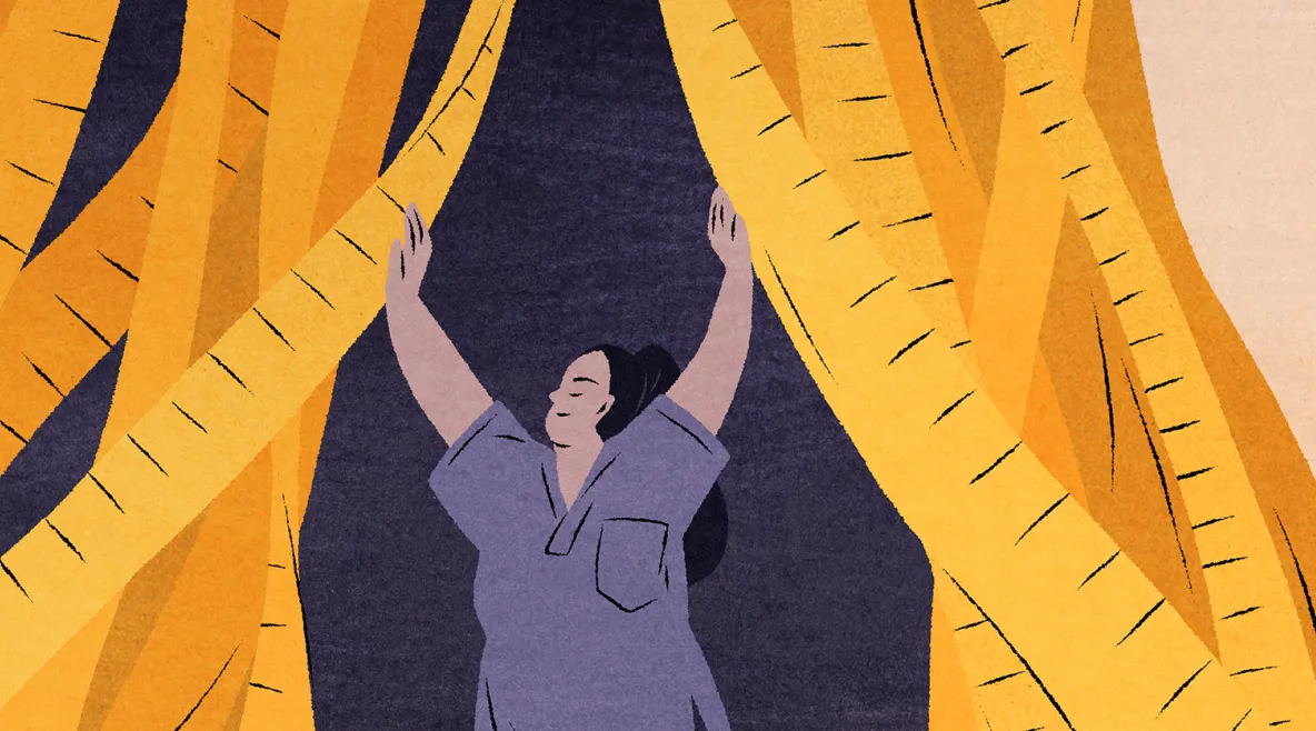 Hoitaja asuun pukeutunut nainen avaa mittanauhoista tehtyä verhoa.