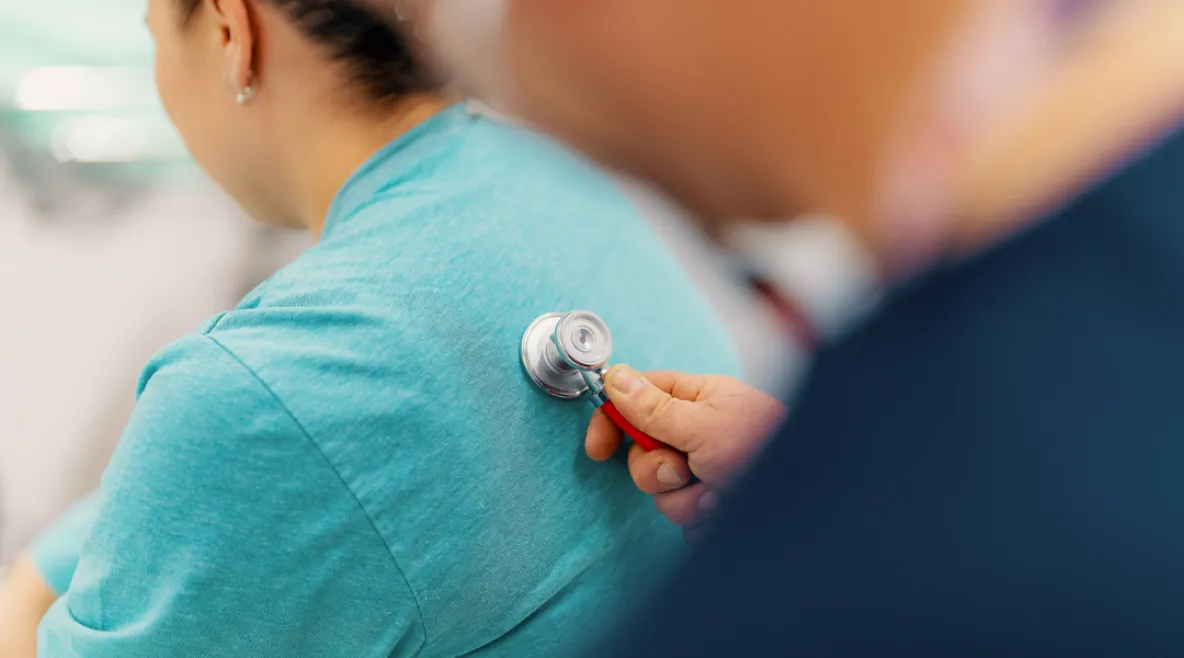 Hoitaja kuuntelee potilaan hengitysääniä stetoskoopilla.