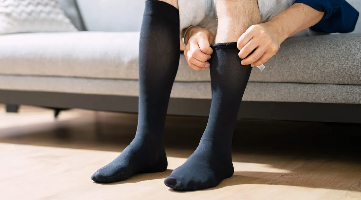 Mies kiskoo kompressiosukkia jalkaansa.