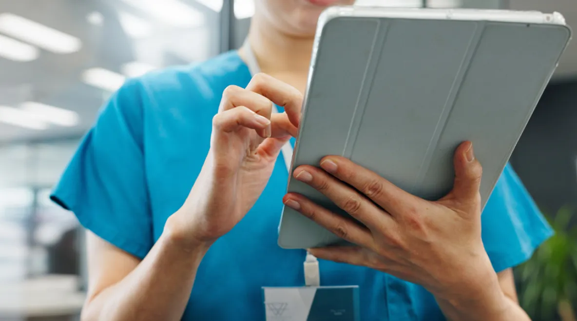 Hoitaja kirjaamassa tai katselemassa tietoja tabletilla.