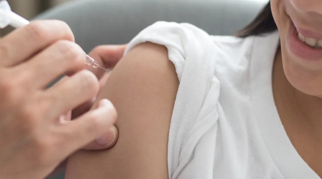 Hoitaja antaa rokotteen nuoren käsivarteen.