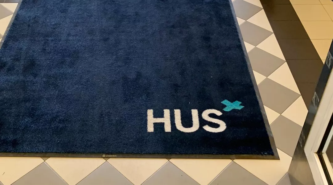 HUS-teksti matossa Kirurgisessa sairaalassa Helsingissä.