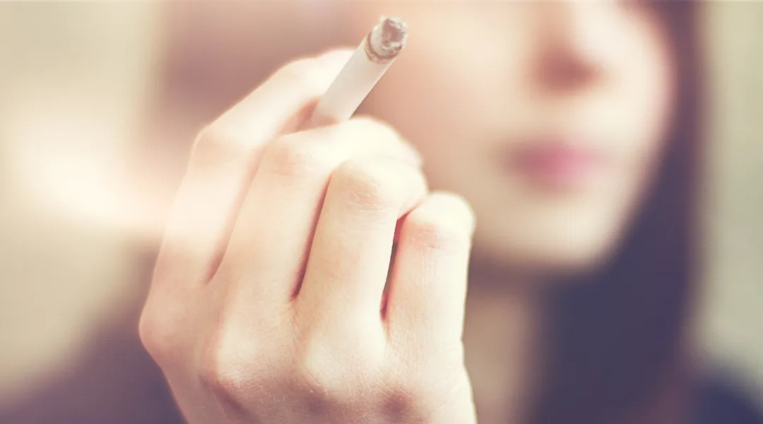 Nuori nainen tupakka kädessä. 