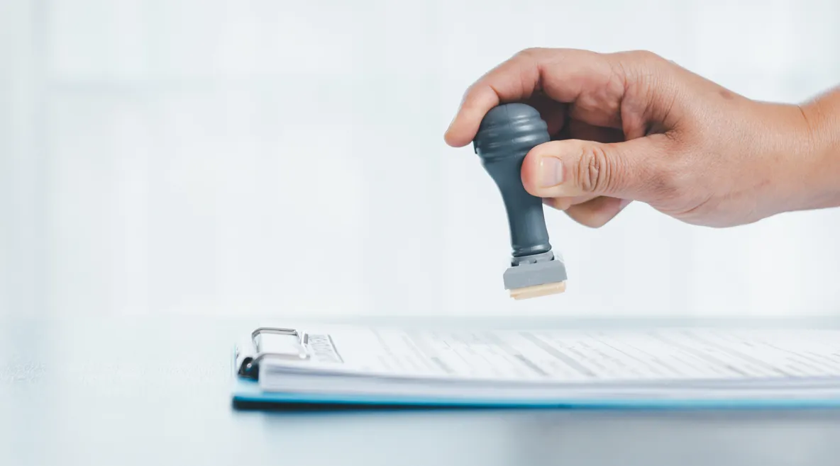 Käsi leimaamassa paperipinoa.