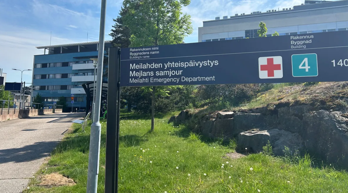 Meilahden sairaala-alue kesällä kuvattuna. Päivystys-kyltti nurmikolla. Hyvinvointialueiden säästöt ja rekrytointikiellot kiristävät sote-alan kesää. 