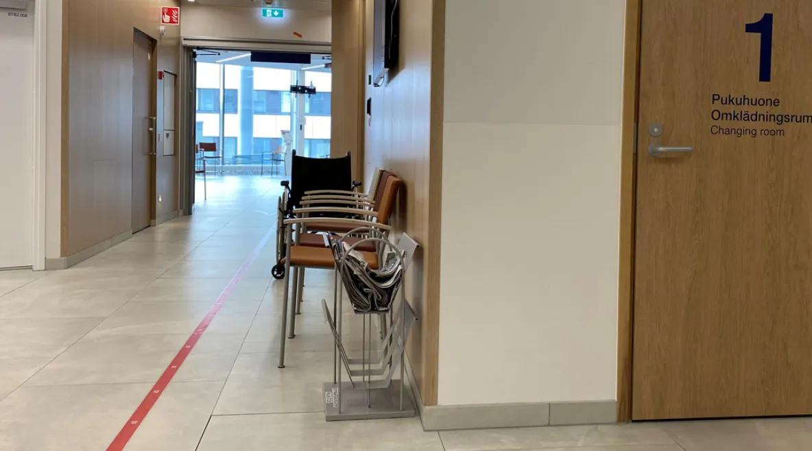 Sairaalan tyhjä käytävä. Seinustalla tuoleja. 