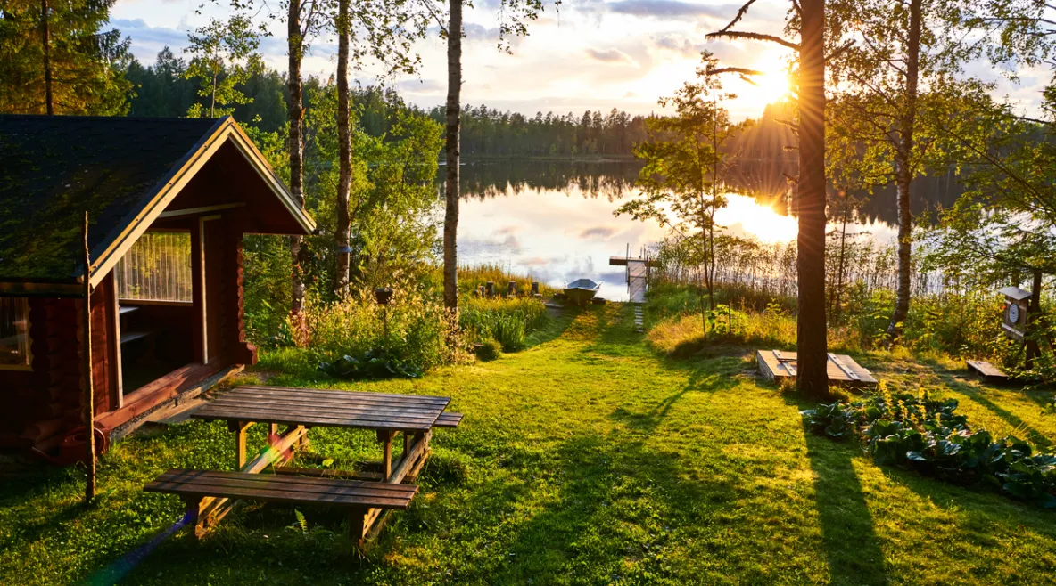 Mökki ja järvenranta auringonlaskussa.