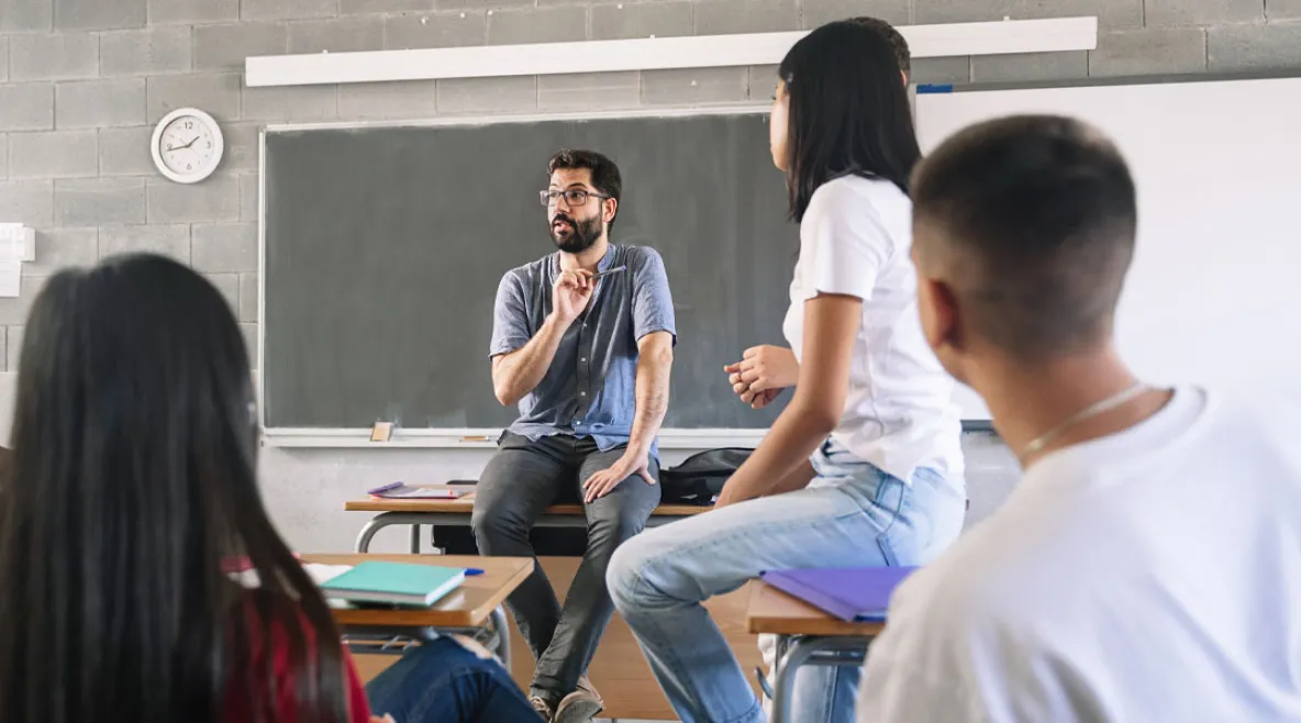 Innostunut miesopettaja puhuu ja oppilaat kuuntelevat kiinnostuneina.