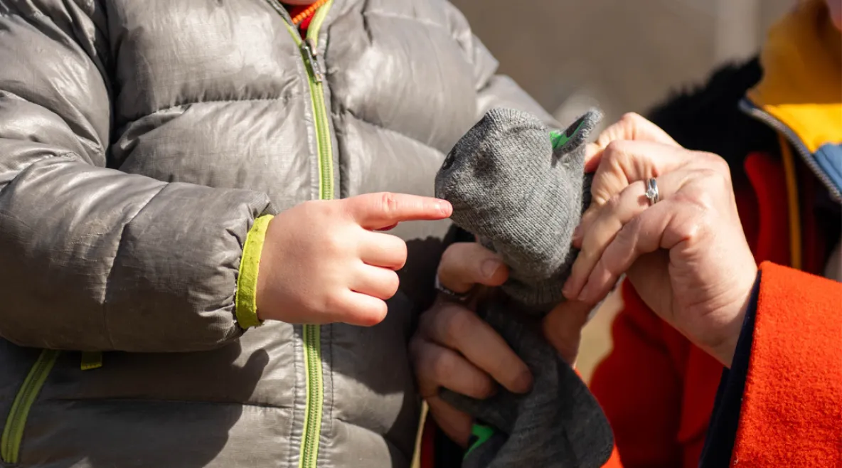 Aikuinen auttaa lapselle lapasia käteen.