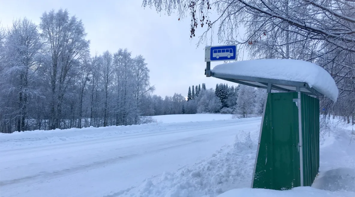 Linja-autopysäkki syrjäseudulla keskellä talvista lumimaisemaa.