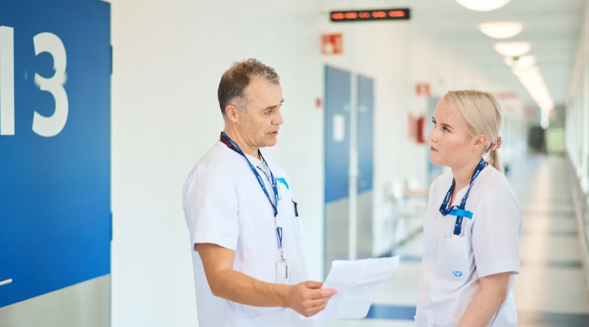 Keusote aloittaa uudet yt-neuvottelut. Kaksi hoitajaa keskustelemassa sairaalan käytävällä.