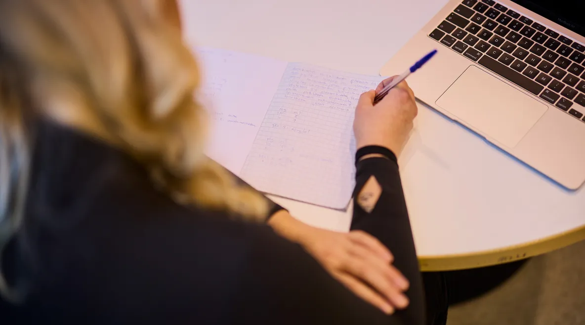 Nainen laskee laskuja paperille. 