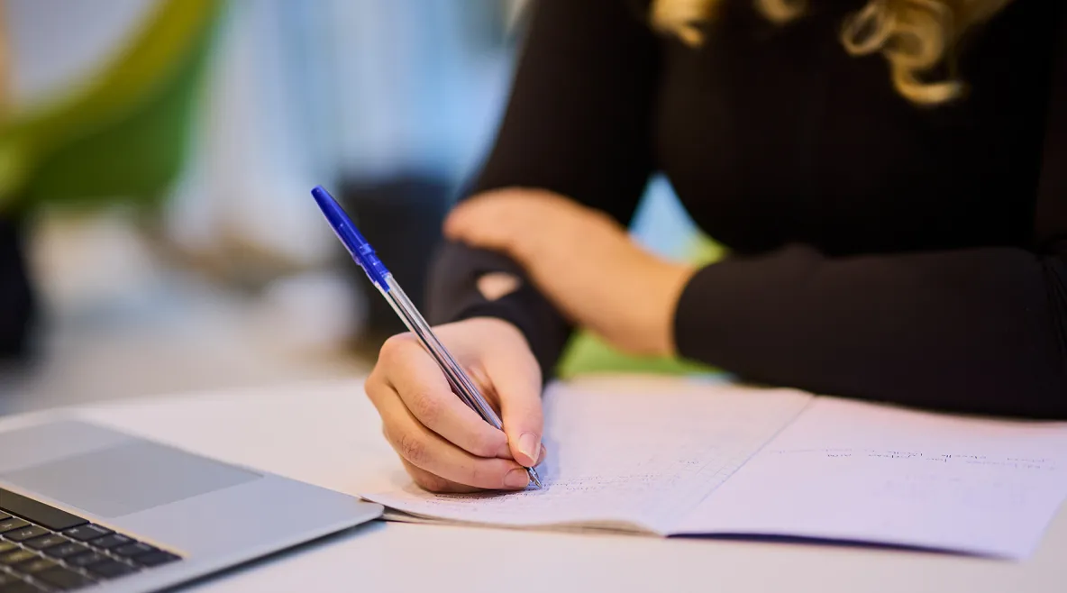 Ihminen laskee kynällä paperille.