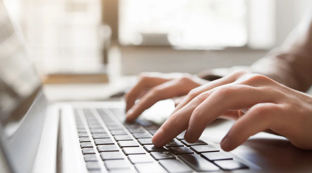 Henkilö kirjoittamassa someen tekstiä kannettavalla tietokoneella.