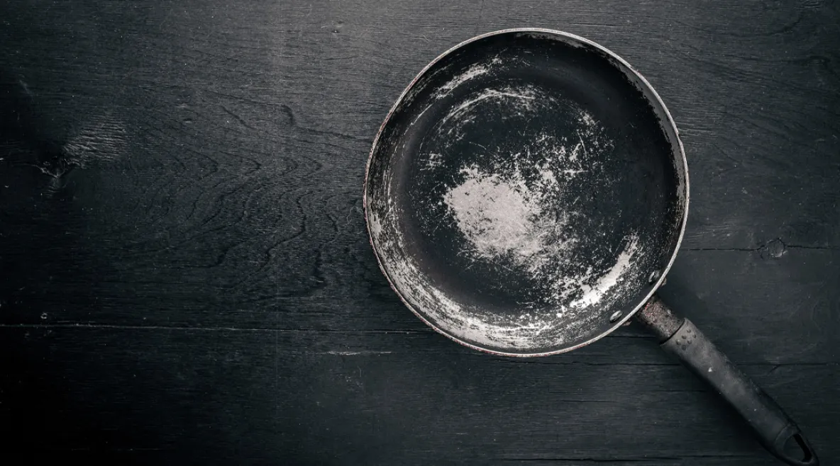 Vanha ja kulunut paistinpannu tumman pinnan päällä.