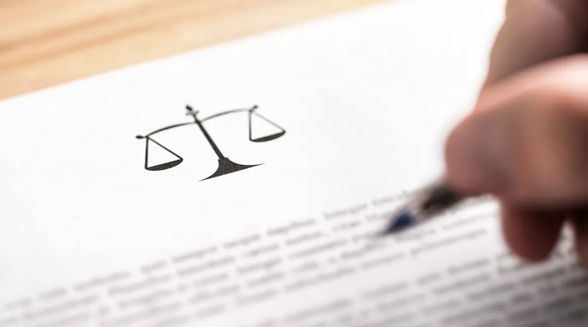 Tuntematon hahmo lukee lakitekstiä kynä kädessä.