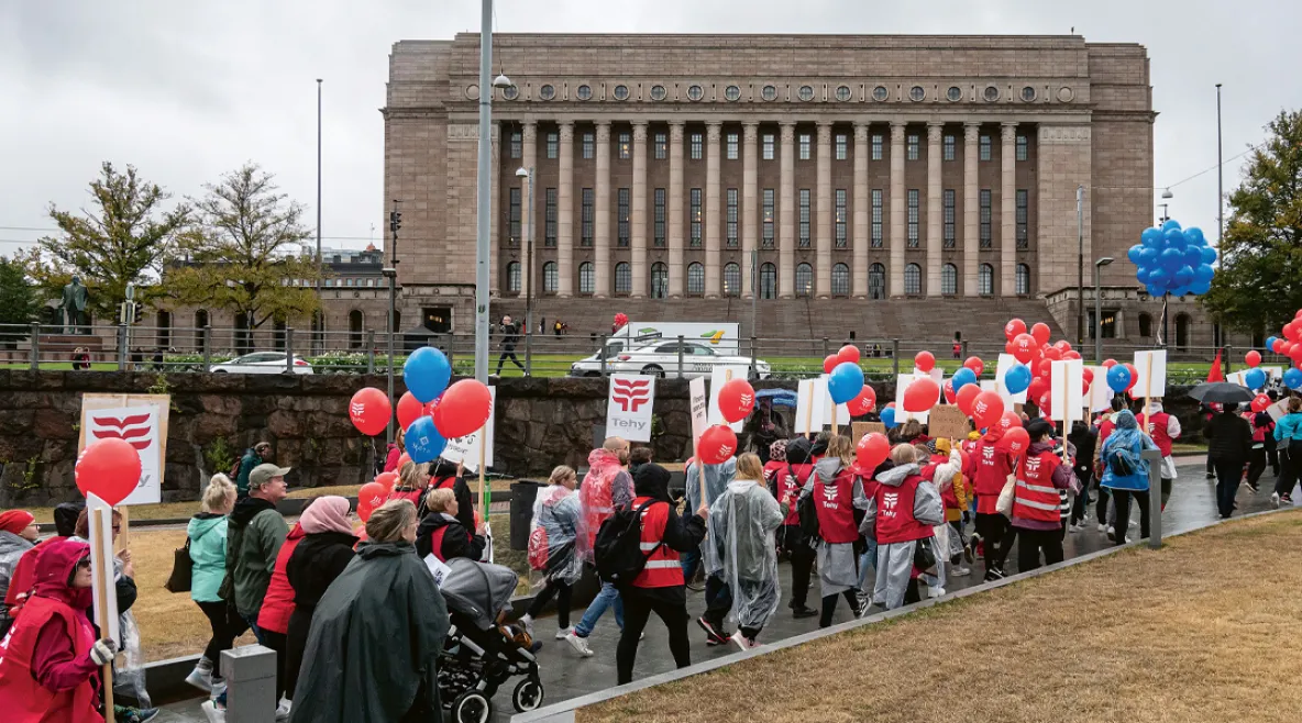 Tehyläisiä mielenosoittajia marssimassa kyltteineen kohti eduskuntataloa.