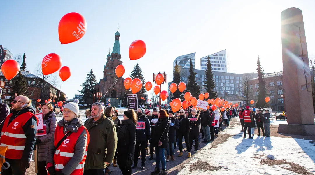 Tehyläiset osoittavat Tampereella mieltä. Kulkueessa ihmisillä punaiset liivit ja punaiset ilmapallot.