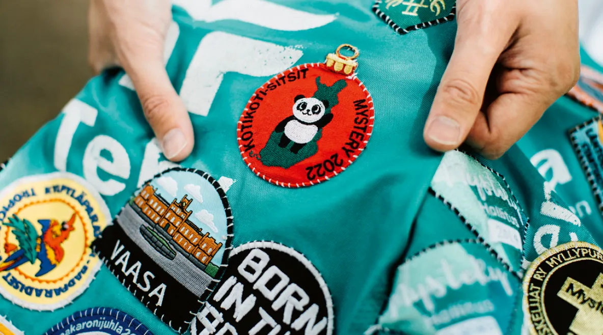 Opiskelija pitää haalaria käsissään ja näyttää siinä olevia haalarimerkkejä.