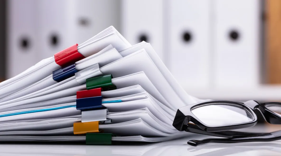 Sopimuspapereita pöydällä.Silmälasit paperipinon vieressä.