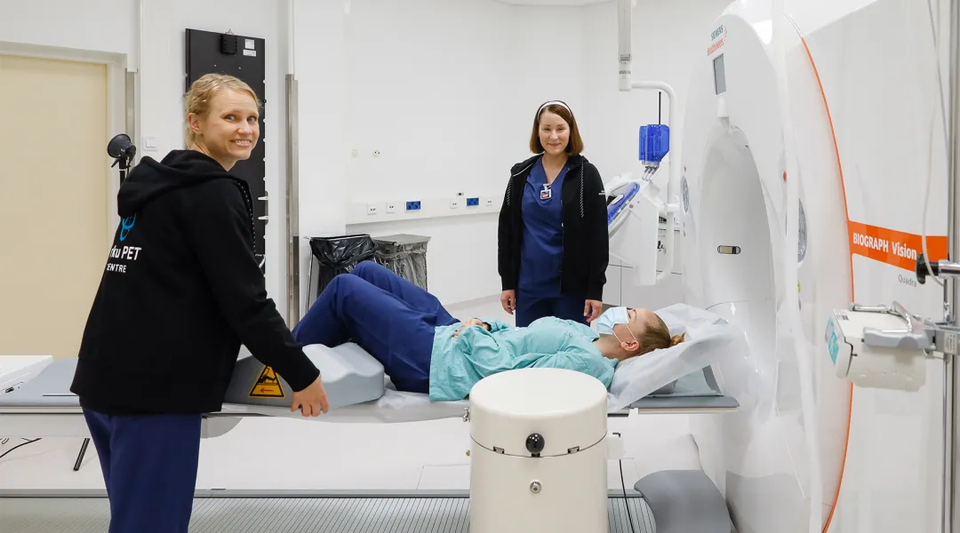 Röntgenhoitajat asettelevat potilasta PET-laitteeseen.