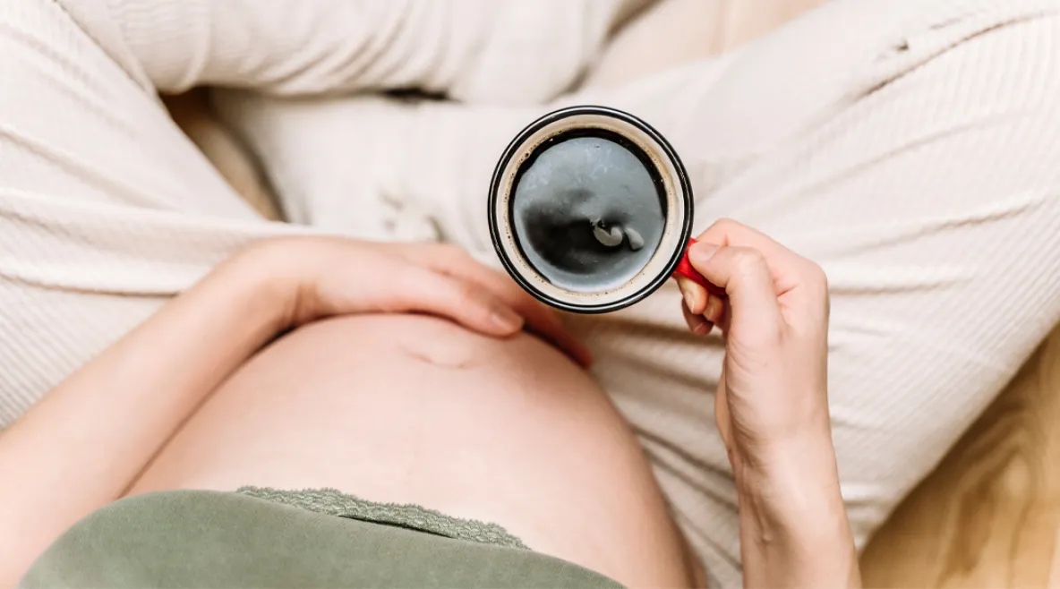 Raskaana oleva nainen juomassa kahvia kupista. Yksi kuppi kahvia riittää väitöksen mukaan raskaana olevalle.