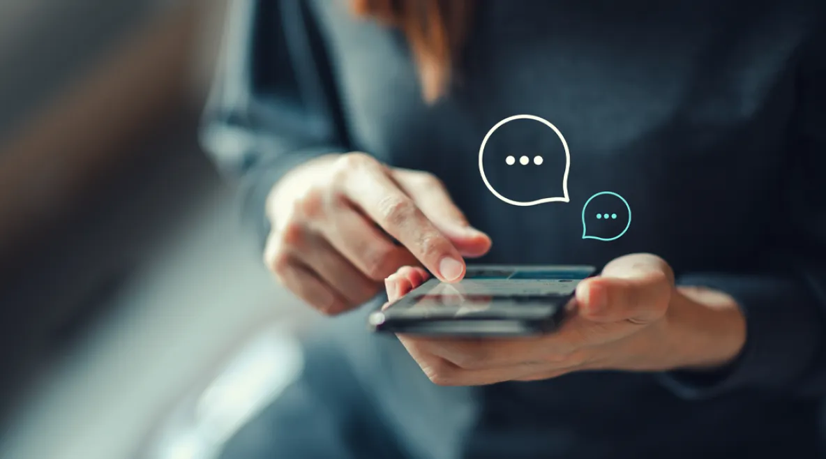 Henkilö pitää puhelinta kädessä ja kirjoittaa chat-tukeen viestiä.