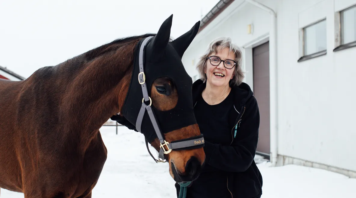 Kirsi Nicklén seisoo hevosen vierellä ulkona.