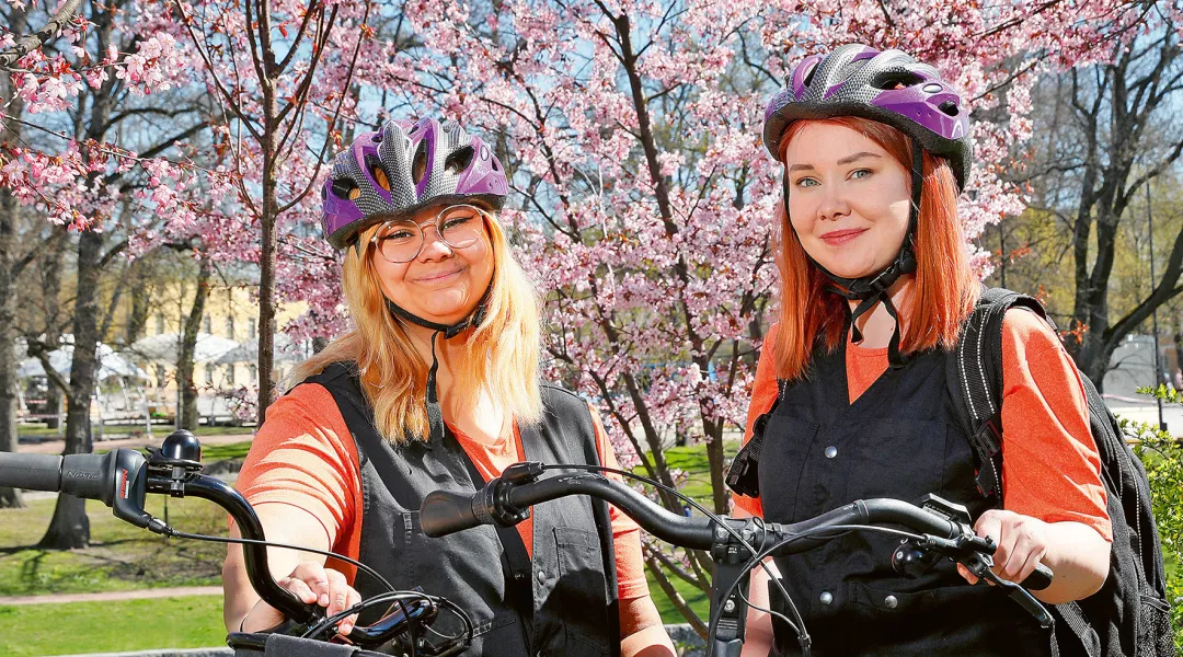 Jasmin Rönkkö ja Samira Grönros pyörineen kukkivien kirsikkapuiden edessä.