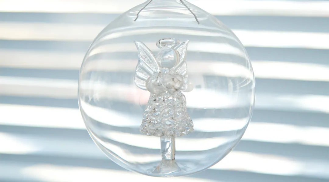 Kuvassa on lasinen enkeli-koriste lasipallossa.