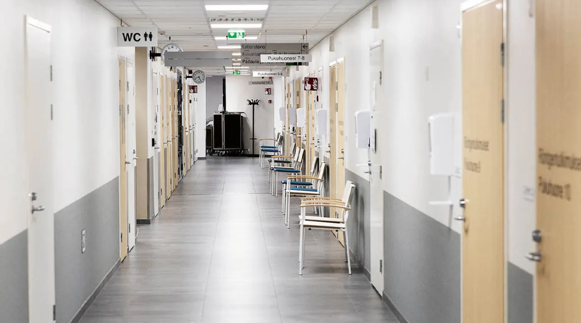 Kuvituskuva sairaalan käytävästä. Tyhjällä käytävällä muutamia tuoleja.