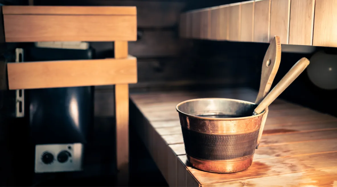 Saunan laiteilla löylykaukalo. Taustalla näkyy kiuas.