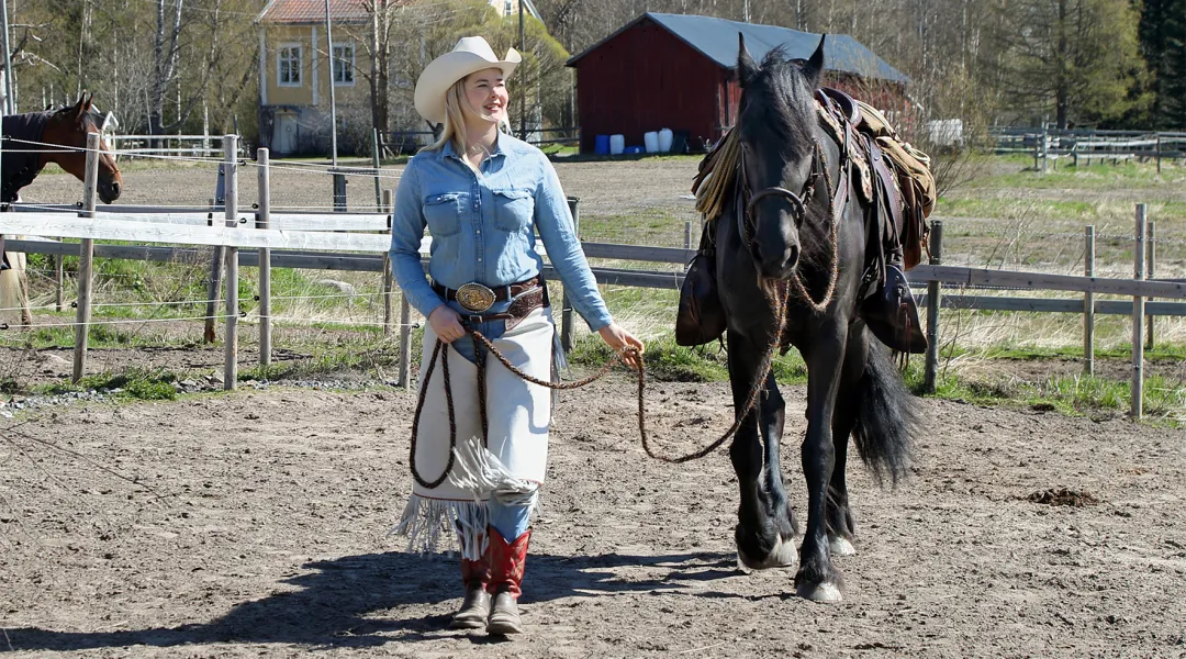 Lännenasuun pukeutunut Rebecca Ylitalo taluttaa hevosta.