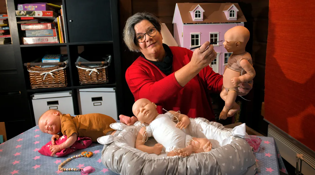 Sairaanhoitaja Marjut Sarka ja kolme reborn-nukkea.