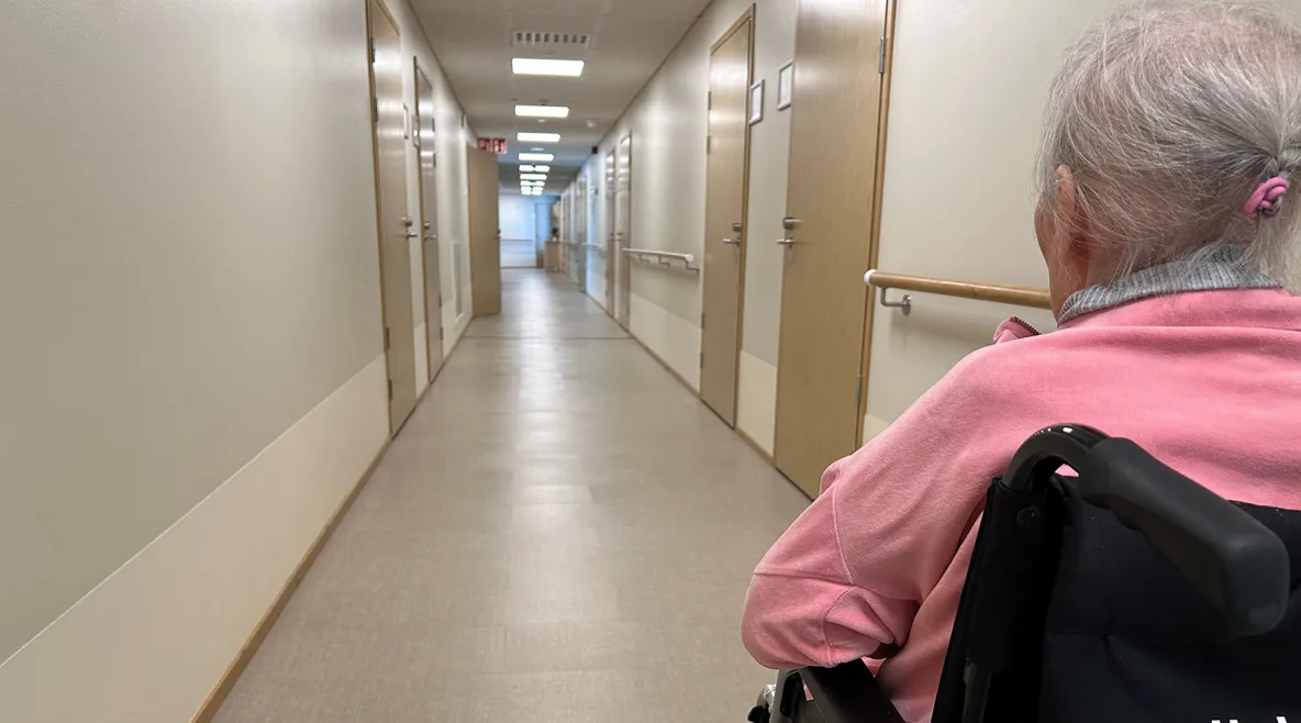 Palvelutalon pitkä käytävä ja vanhus pyörätuolissa.