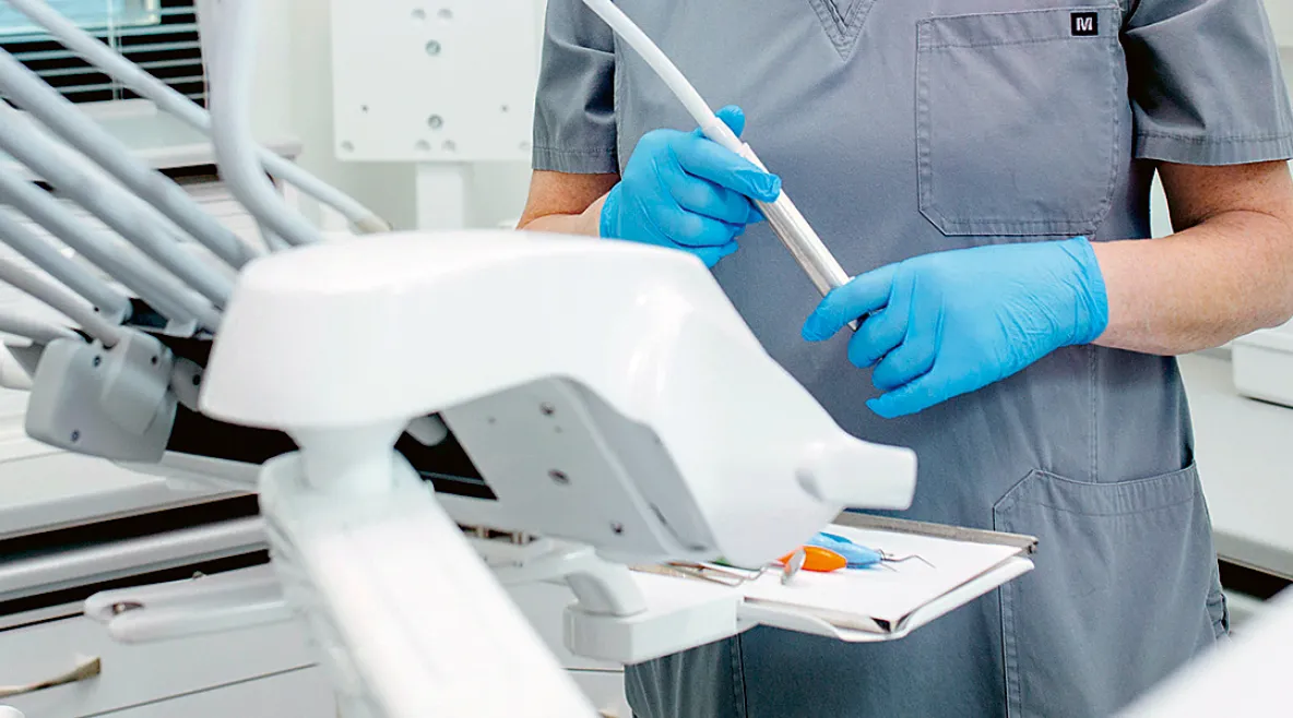 Suuhygienisti työvälineidensä äärellä suojahansikkaat kädessä.