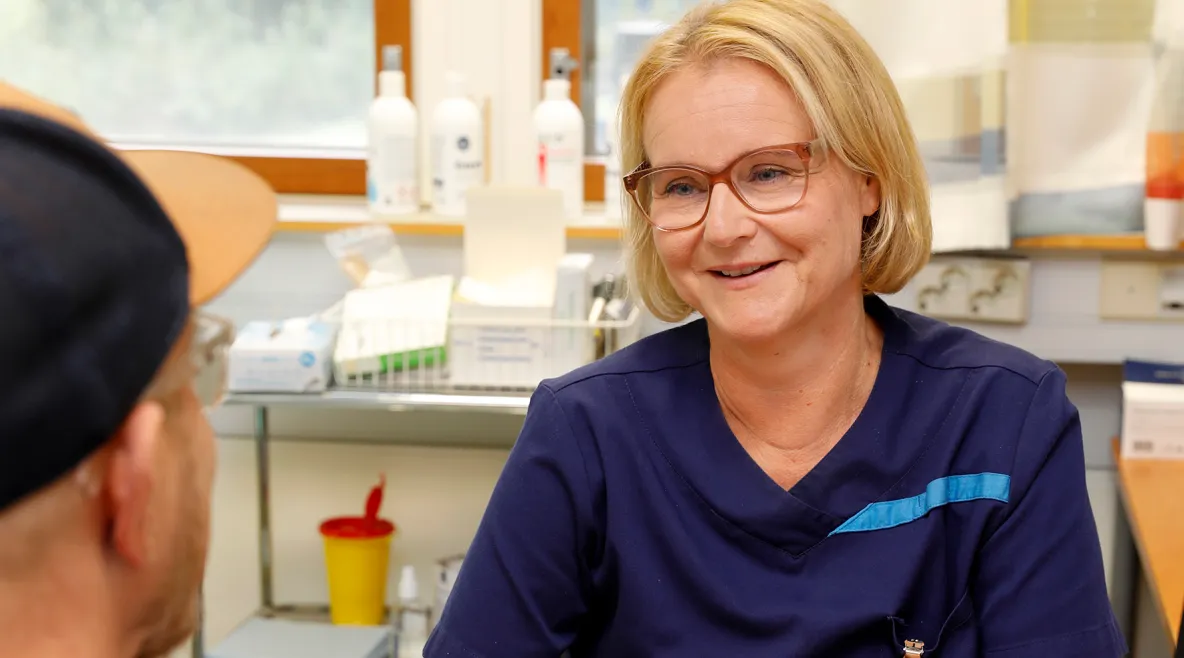 Heidi Salmenoja työpöydän takana, toisella puolella potilas.