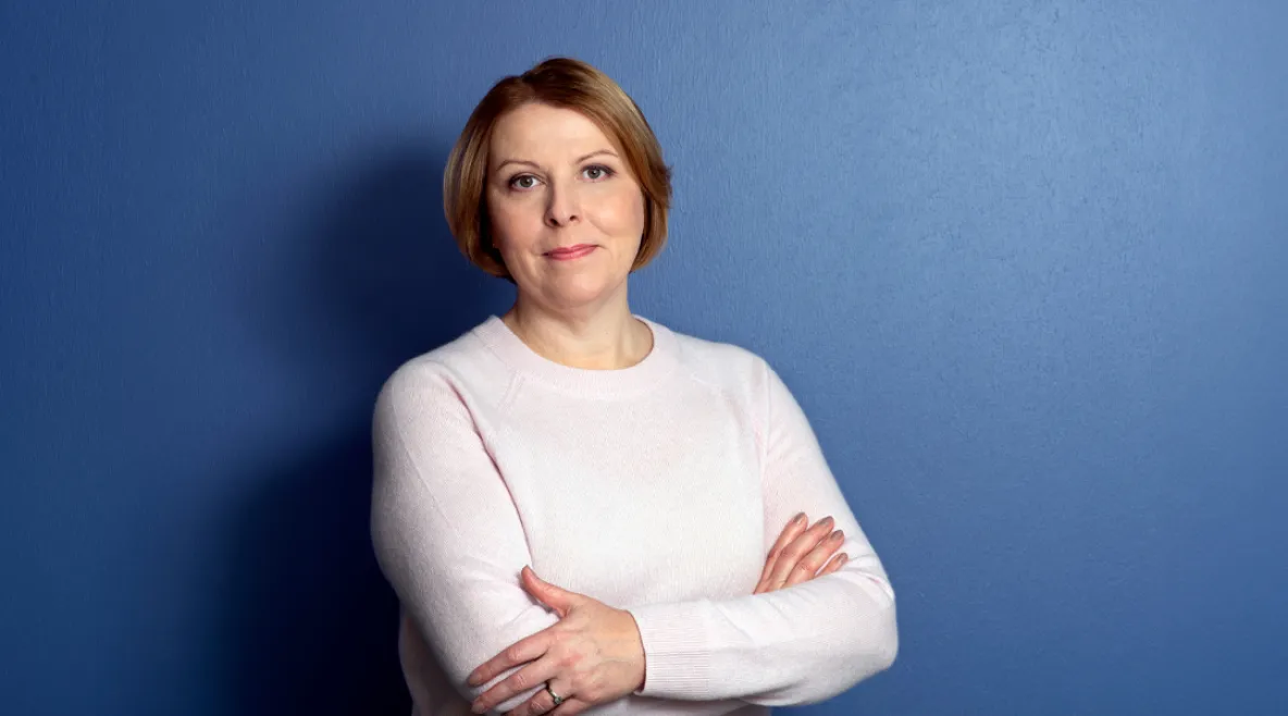 Tehyn toiminnanjohtaja sekä edunvalvontajohtaja Else-Mai Kirvesniemi katsoo hymyillen kameraan sinistä taustaa vasten.